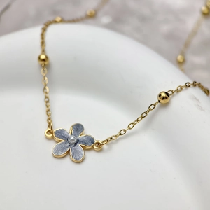 Macro shot of gold flower pendant with marble texture and pearl on a beaded chain