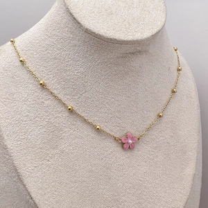 Gold chain necklace with pink flower pendant and small beads displayed on neck model