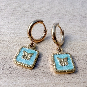 Detailed view of 18K gold hoop earrings with light blue enamel butterfly charms