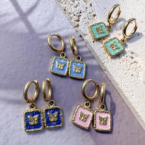 18K gold butterfly enamel earrings set in blue pink and green on purple textured background