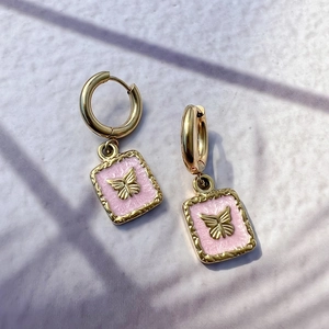 Macro detail of 18K gold-plated butterfly drop earrings with pink enamel inlay