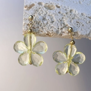 Vue détaillée de boucles d'oreilles fleurs en cristal jaune sur pierre blanche