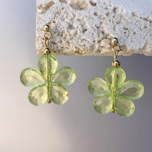 Détail d'une boucle d'oreille fleur en cristal vert clair avec tige en métal doré