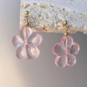 Gros plan de boucles d'oreilles fleurs en cristal rose avec clous dorés sur pierre