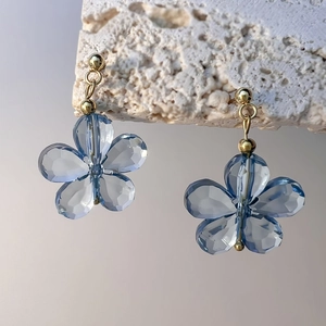 Gros plan détaillé des boucles d'oreilles fleurs en cristal bleu et accents dorés