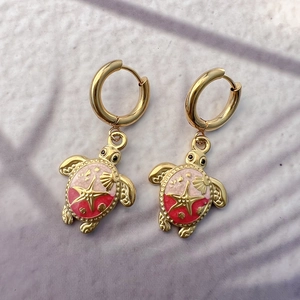 Detailed view of turtle earrings with pink gradient enamel shell and golden starfish