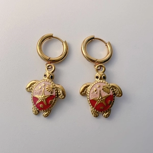 Detail of 18K gold-plated turtle earrings with colorful enamel and starfish accents