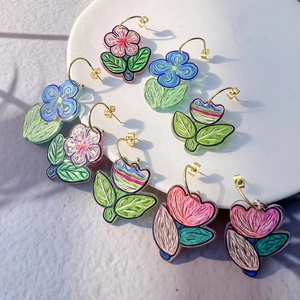 Colorful floral C-shape earrings with hand-painted patterns on white display tray