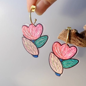 Close-up of floral acrylic earrings with hand-painted pink and green stripe patterns