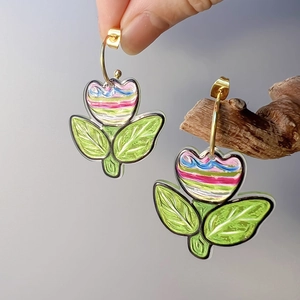 Detail of colorful hand-painted flower earrings with 18K gold hooks and green leaves