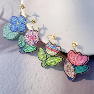 Macro detail of hand-painted floral C-shaped earrings with unique artistic oil brush textures