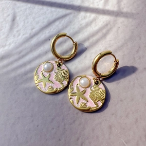 Detailed macro view of 18K gold plated earrings with starfish, shell and pearl charms