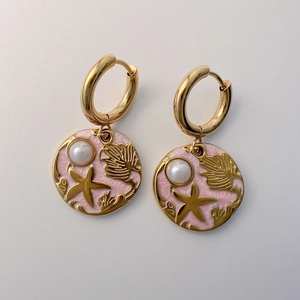 Close-up of pink enamel ocean earrings with gold starfish, shells and pearl details