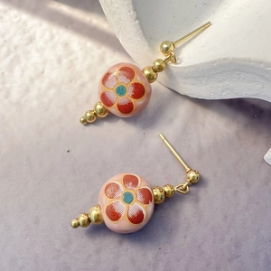 Macro detail of ceramic plum blossom earrings with gold-plated stainless steel accents