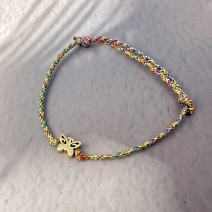 Colorful hand-woven cord bracelet featuring a gold hollow butterfly pendant and adjustable knot