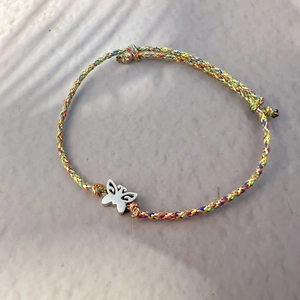 Detailed close-up of handmade woven colorful rope bracelet with silver butterfly charm