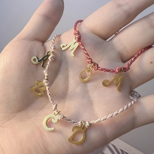 DIY alphabet charm bracelets with pink and red woven cords and gold metal pendants