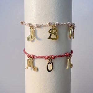 Detail of DIY braided rope bracelets with gold MOM charms on a display stand