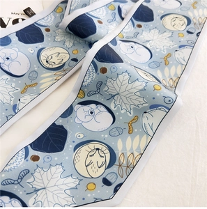 Close-up of a blue floral skinny scarf with sleeping bear pattern and leaf details