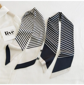 Detail of elegant black and white striped long narrow silk scarf displayed on a white shirt