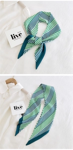 Detail of a long narrow silk-like scarf with green and blue diagonal stripes on a white shirt