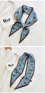 Detail of blue printed twilly silk scarf tied as a bow on white shirt with MOORE pattern