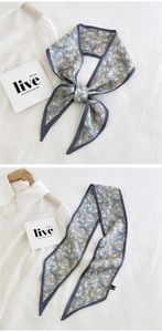 Detailed view of leaf print narrow silk scarf tied as bow and hanging on a hanger