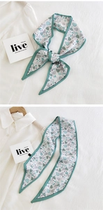 Detail of mint green leaf pattern narrow scarf tied as a bow on a white shirt