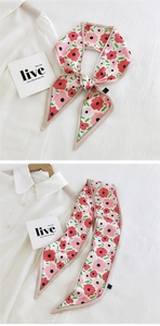 Detail of pink floral silk scarf tied elegantly on white shirt with beige hem finish