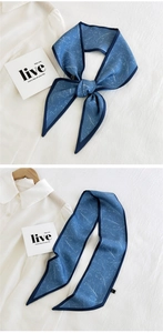 Detailed view of dark blue long silk scarf tied as a bow on a white shirt collar