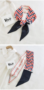 Detail of a red heart pattern twilly scarf styled as a necktie on a white blouse