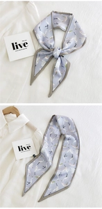 Detail of light blue silk scarf featuring crane print and gray piping edges on white shirt