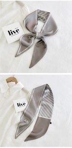 Detail of grey satin skinny scarf with white edges and Kk logo print on white shirt