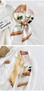 Détail d'un foulard twilly en soie à motifs géométriques noué sur une chemise blanche