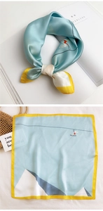 Detail of light blue silk scarf with yellow borders and creative surfing prints
