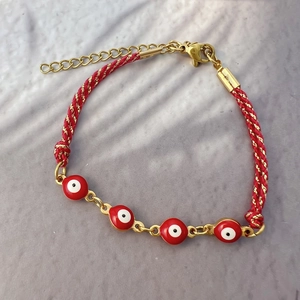 Dettaglio del bracciale occhio greco intrecciato a mano con perle rosse e chiusura 18K oro