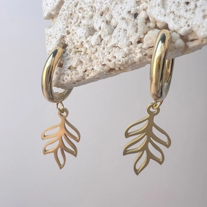 Detailansicht der goldenen Blatt-Ohrringe mit hohlen Palmenblatt-Anhängern auf Stein