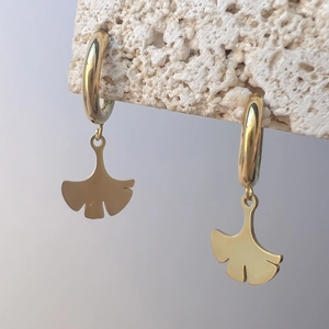 Detailaufnahme goldener Ginkgo-Blatt-Ohrringe aus Edelstahl an einem steinernen Halter