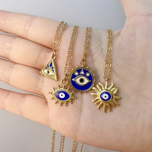 Set of 4 gold evil eye necklaces in geometric shapes held in hand for size reference