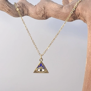 Detail of gold evil eye pendant on a branch showing fine craftsmanship and textures