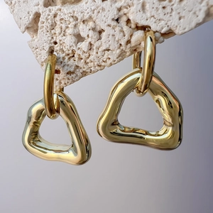 Macro view of gold geometric hollow triangle earrings with a molten texture on stone