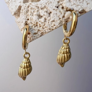 Detailed close-up of 18K gold sea shell pendant hoop earrings on white stone