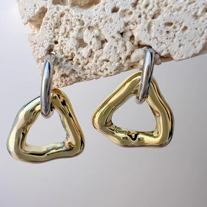 Close-up of geometric hollow triangle earrings on a textured stone display stand