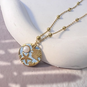 Detail of 18K gold starfish and shell pendant with blue enamel and pearl on fine chain