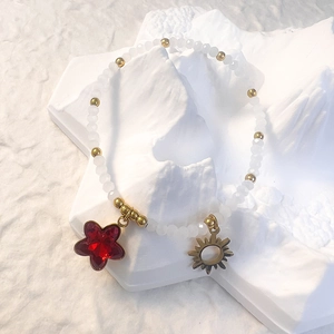 Detail of beaded bracelet with white frosted beads and red star stone pendant