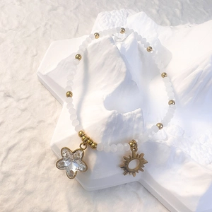 Close-up of frosted white beads bracelet with gold star crystal and sun charms
