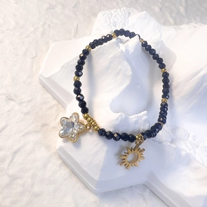 Detailed shot of black glass beaded bracelet with gold star and sun charms on white decor