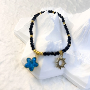 Detail of black faceted beads with gold sun and blue star charms on mountain stand