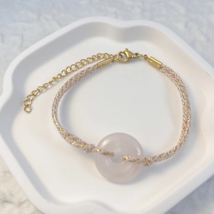 Detailed view of woven pink cord bracelet featuring a natural quartz donut stone charm
