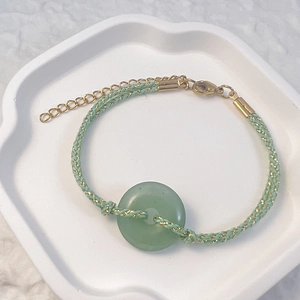 Detail of hand-woven bracelet with green natural stone donut and adjustable gold clasp